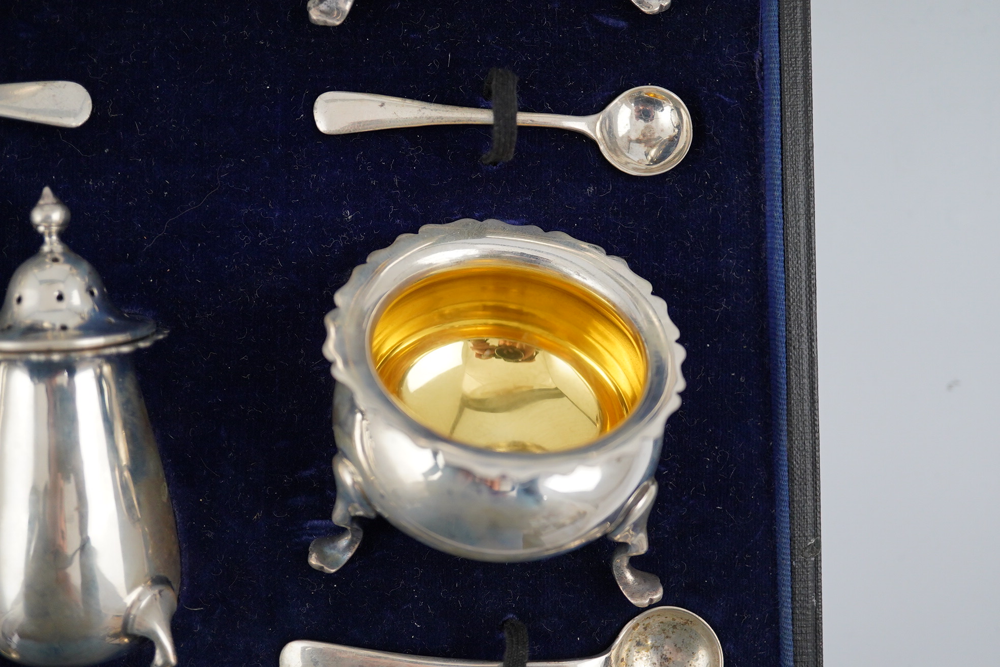 A George V cased silver seven piece condiment set by Horace Woodward & Co Ltd, Birmingham, 1918, with five associated silver condiment spoons. Condition - poor to fair
